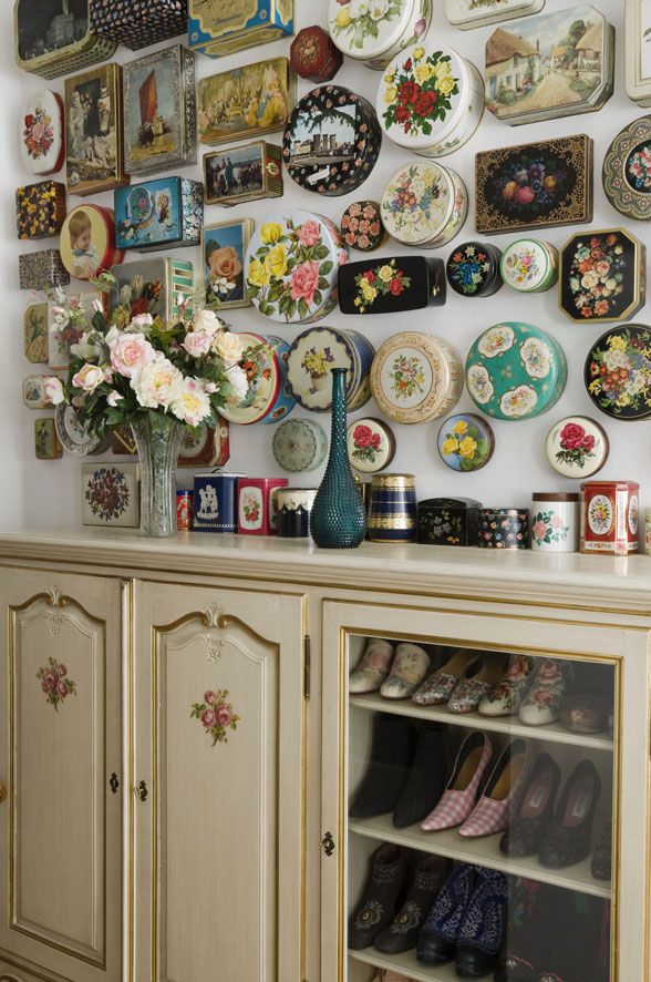 a wall full of plates and vases on top of a wooden table next to a cabinet