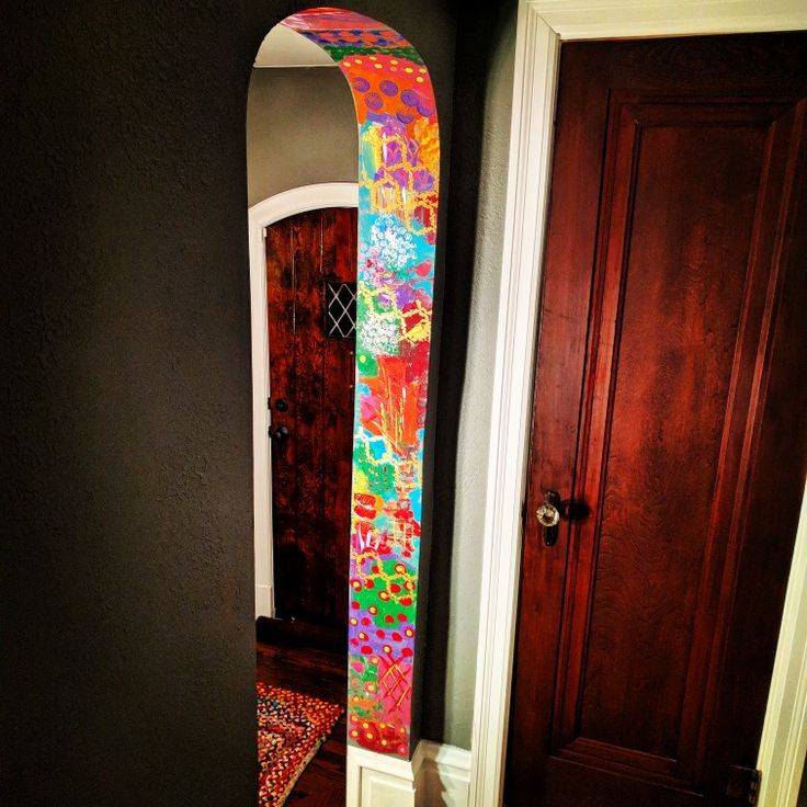 the door is open and there is a brightly colored surfboard leaning up against the wall