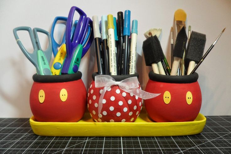 a yellow tray holding two red cups filled with pens and pencils