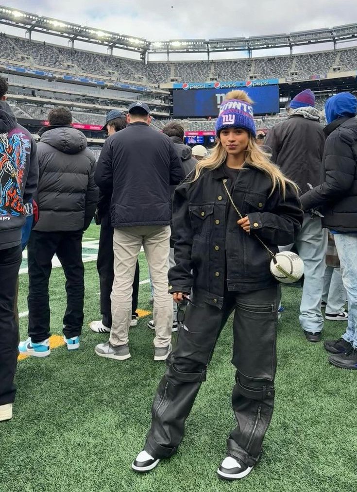 a woman standing in the middle of a field at a football game with other people