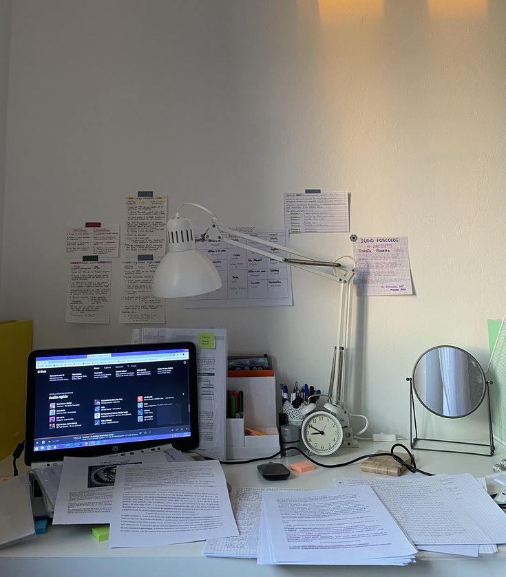 an office desk with papers and a computer monitor on it, along with other items