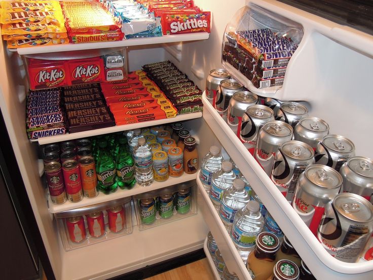 an open refrigerator filled with lots of food and drink cans on the shelves next to each other