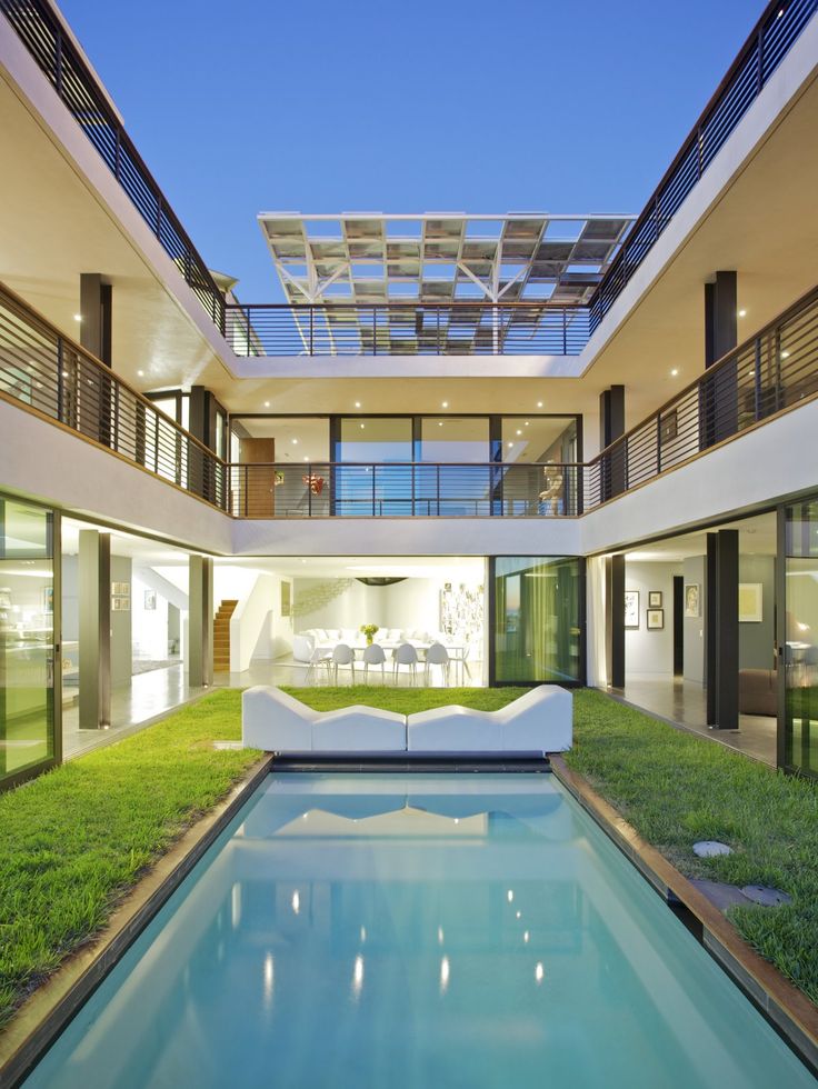 an indoor swimming pool in the middle of a large house with grass on both sides