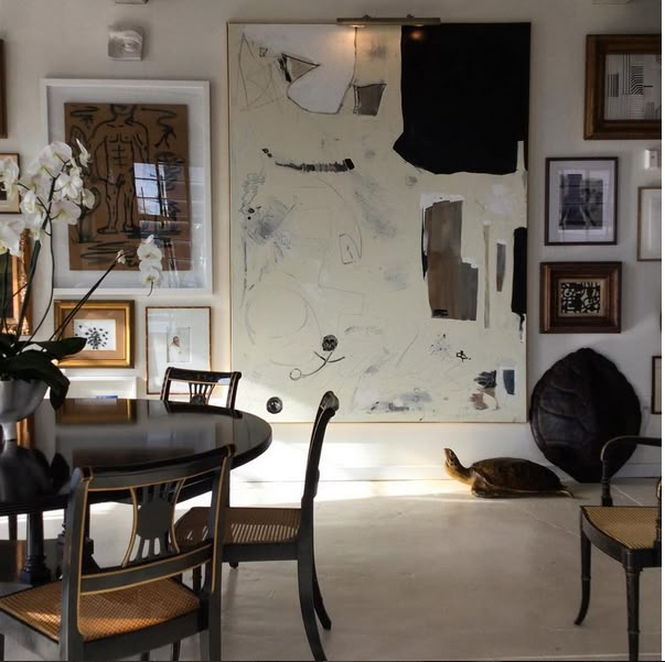 a dining room table with chairs and pictures on the wall