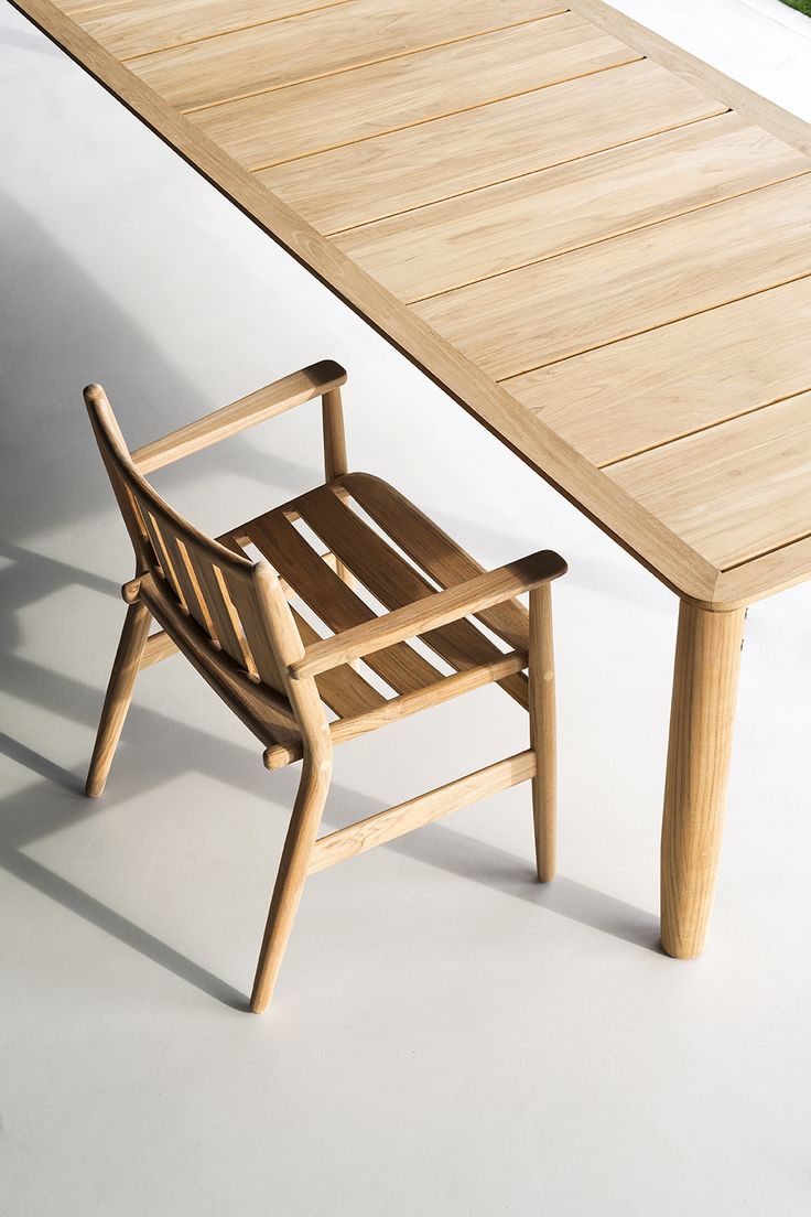 a wooden chair sitting next to a table on top of a white floor with grass in the background