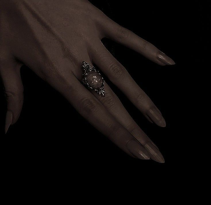 a woman's hand with an ornate ring on her left hand, against a black background