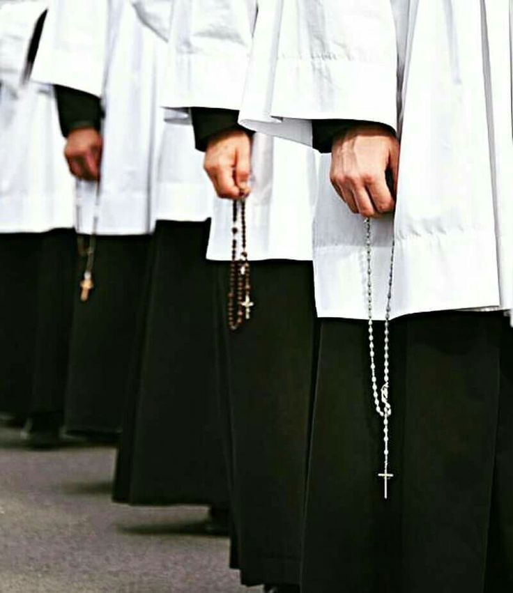 a group of men in white robes holding rosarys