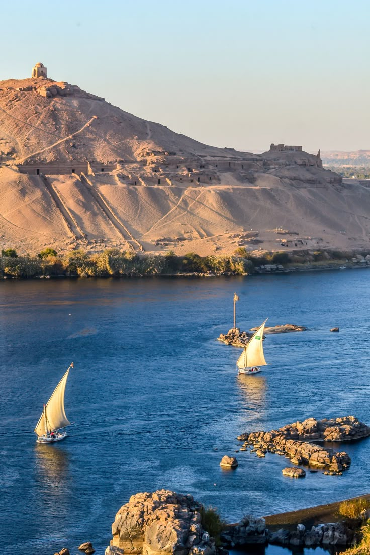 three sailboats in the water near an island