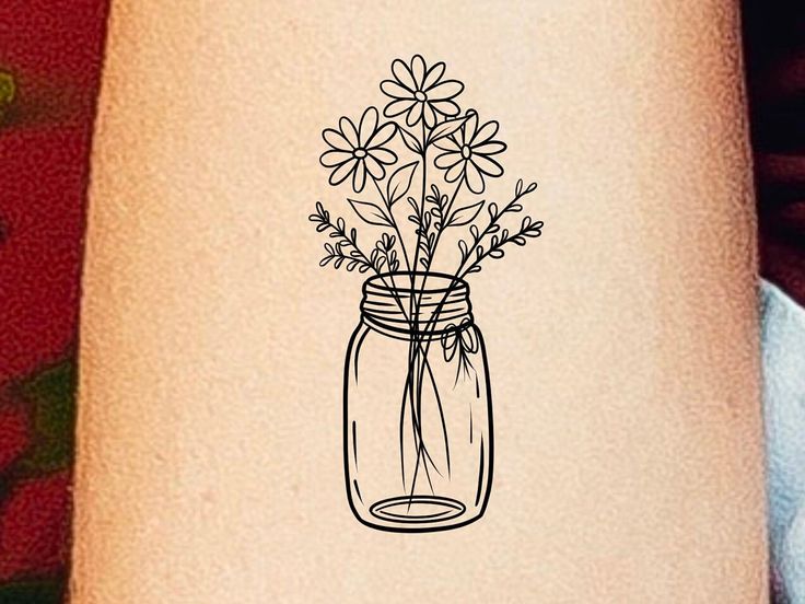 a drawing of flowers in a mason jar on a woman's right arm,