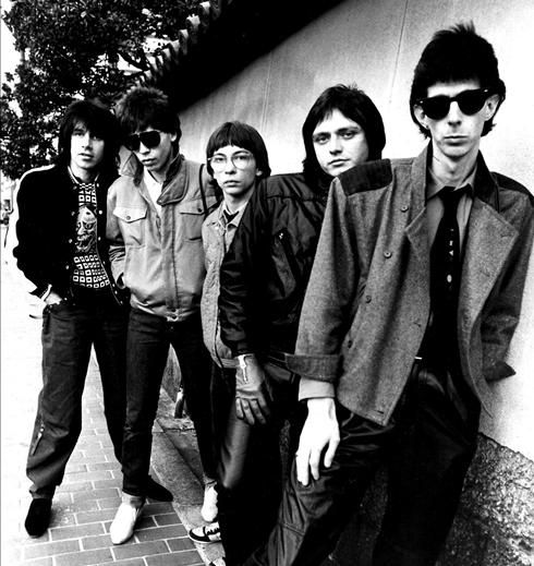 a group of young men standing next to each other on a sidewalk in front of a building