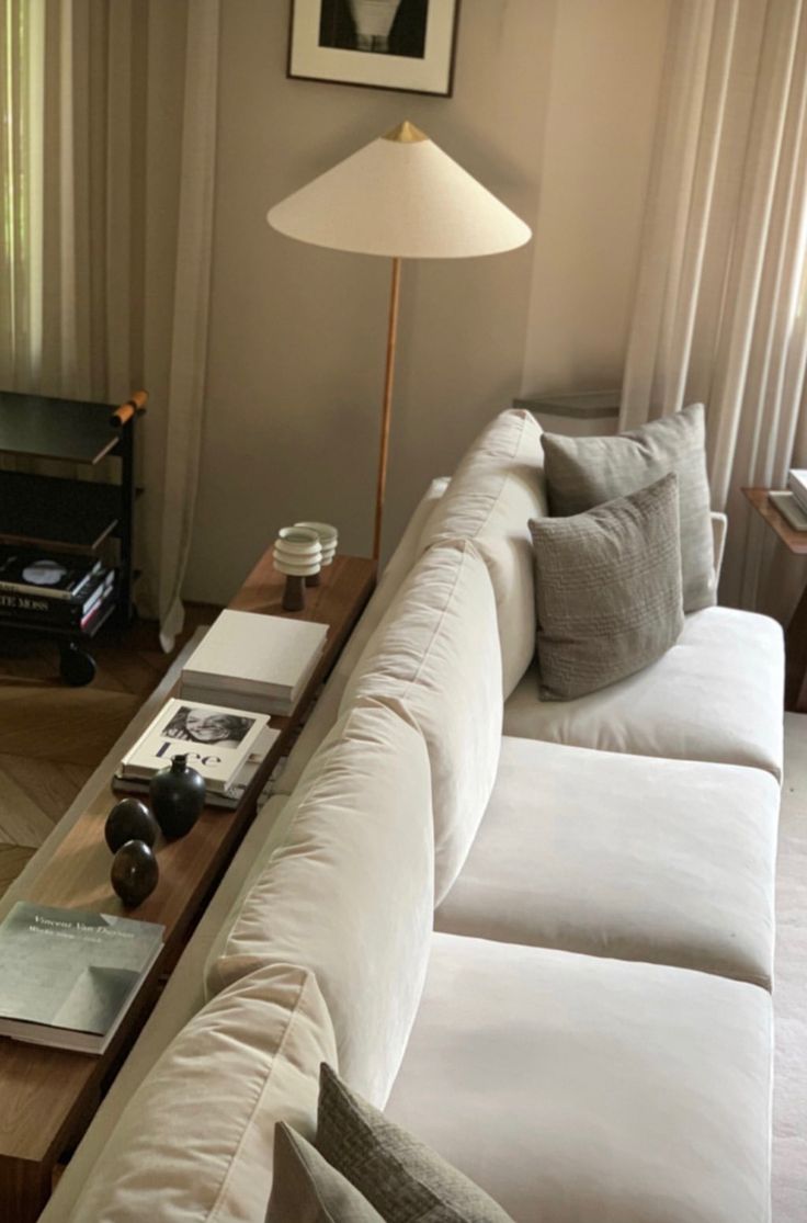 a living room filled with white couches next to a lamp and window sill