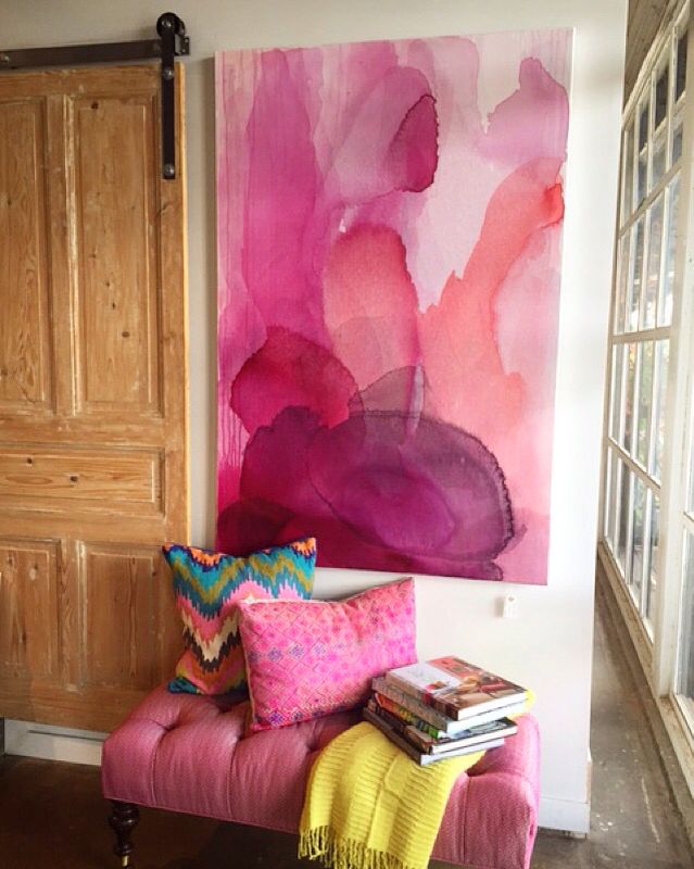 a living room with a pink couch and painting on the wall next to an open door