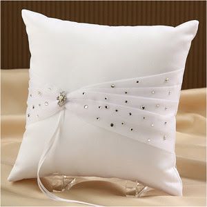 a white pillow with a bow on the side and beaded ribbon at the back