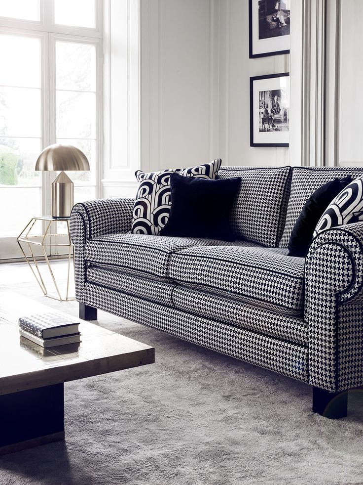 a living room with black and white couches, pillows and pictures on the wall