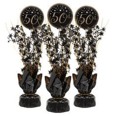 three black vases filled with flowers and balloons for the 50th birthday party on display