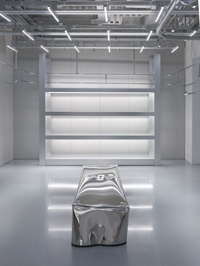 a shiny silver object is sitting in the middle of a room with white walls and flooring