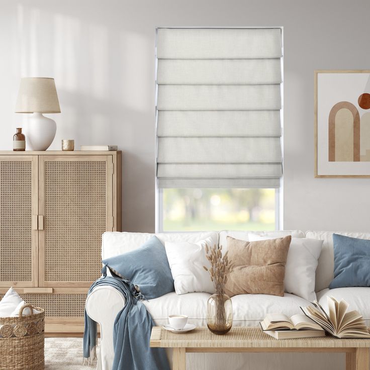 a living room filled with furniture and a window covered in roman blind shades on the windowsill