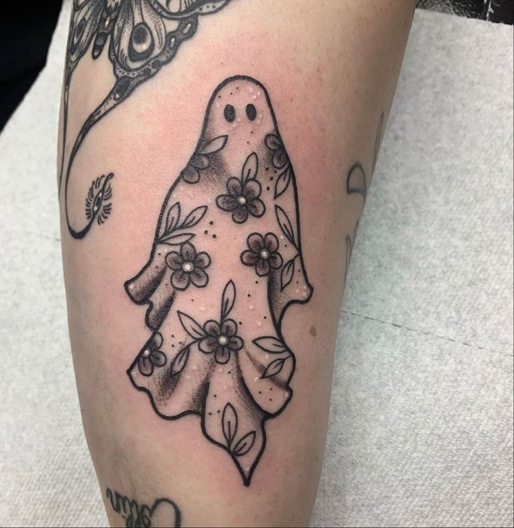 a black and white tattoo of a ghost with flowers