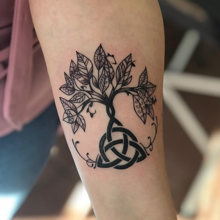 a woman's arm with a tattoo on it and a tree in the middle