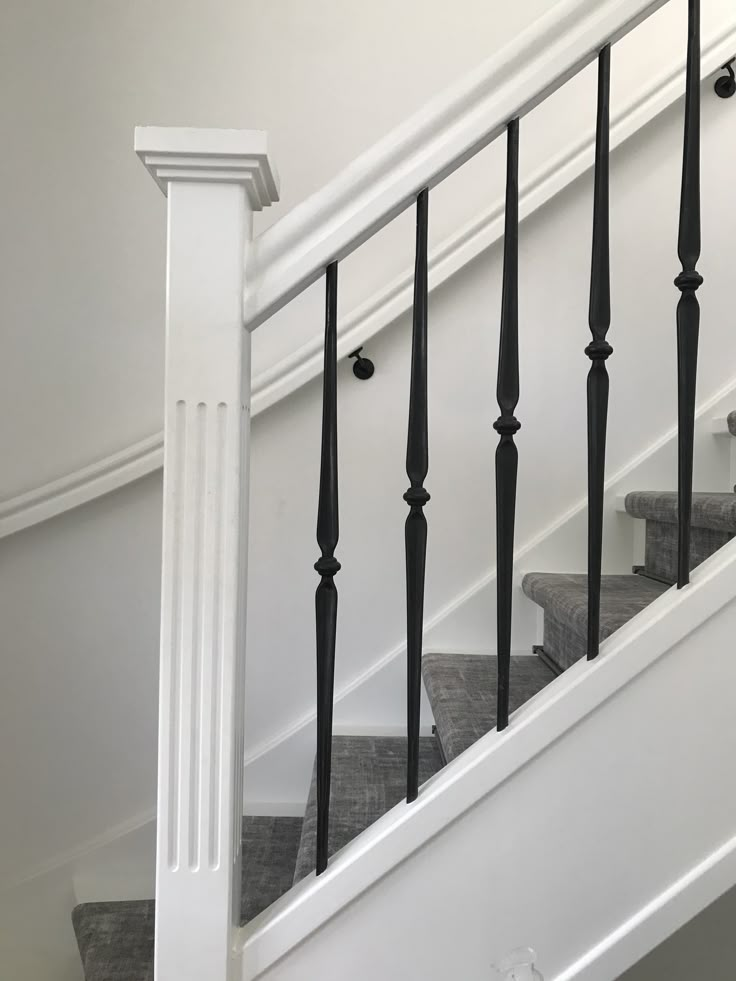 a white staircase with black railing and handrails