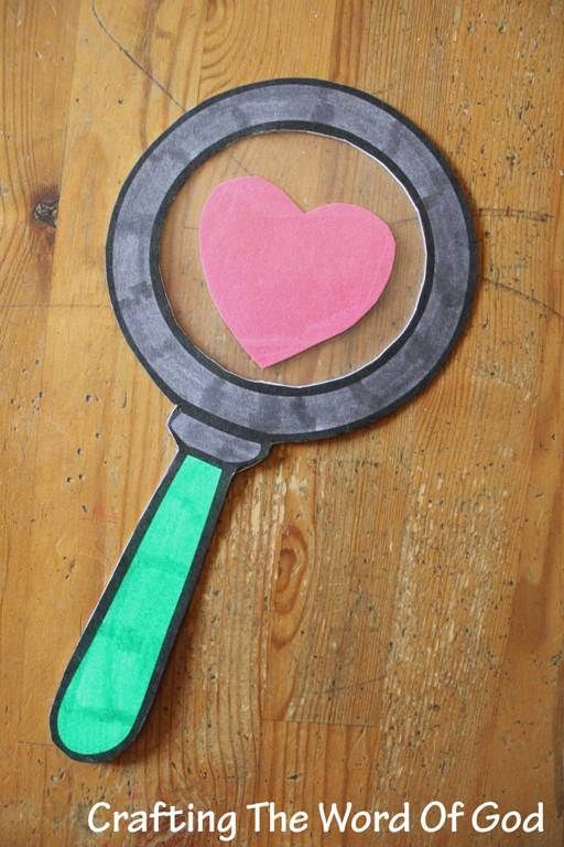 a magnifying glass with a pink heart on it sitting on top of a wooden table