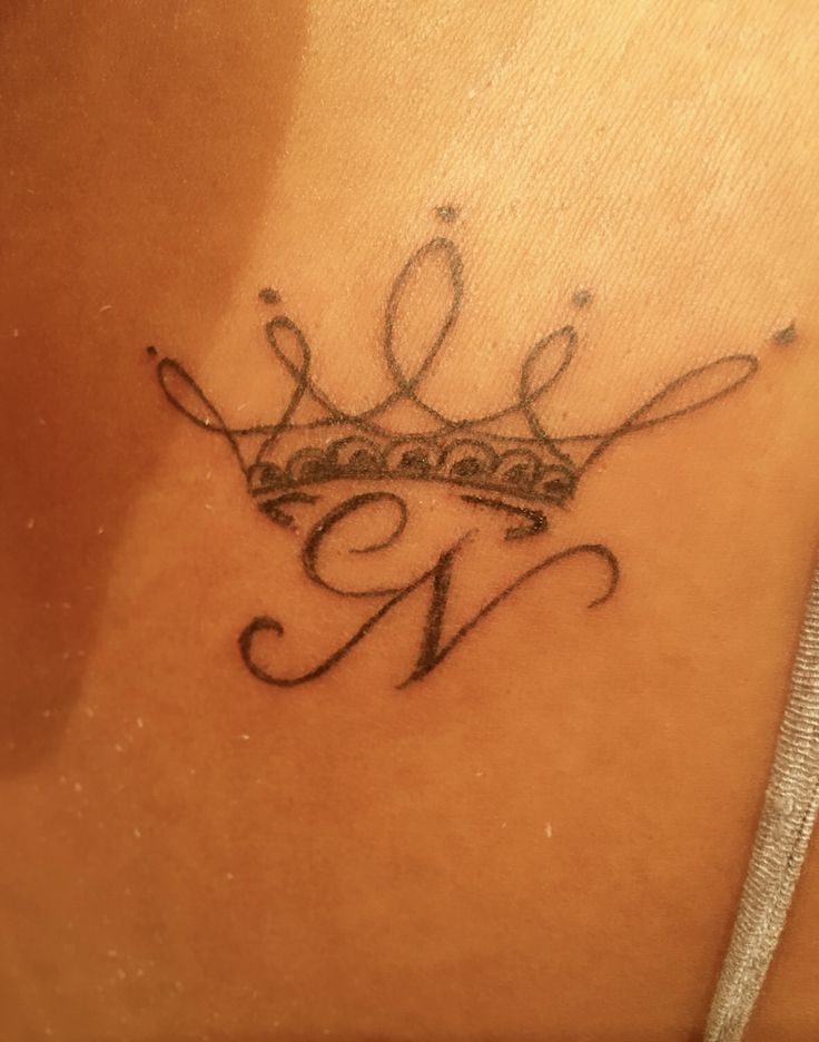 a woman's lower back tattoo with a crown on it