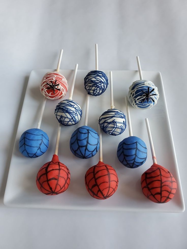 six cake pops with spiderman designs on them sitting on a white plate next to each other