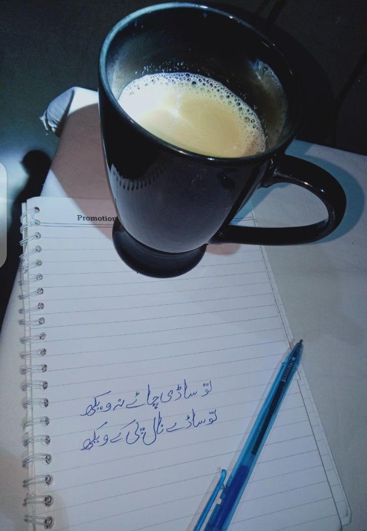 a cup of coffee sitting on top of a notebook next to a pen