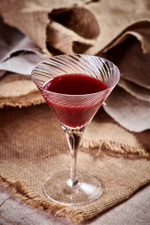 a glass filled with red liquid sitting on top of a table next to burlocks