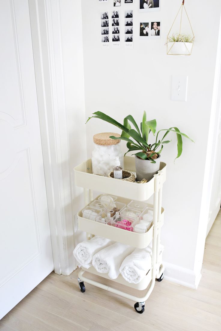 a white shelf with towels and plants on it