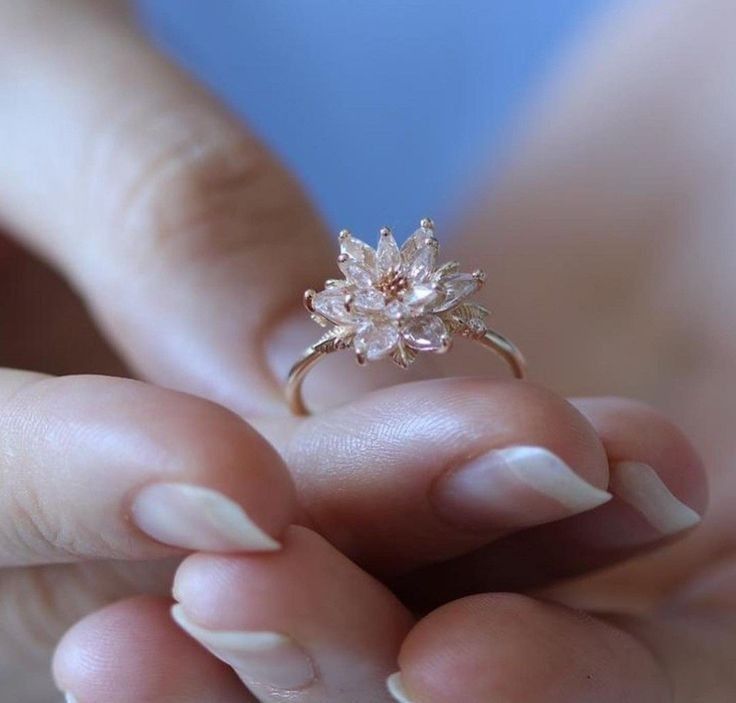 a close up of a person's hand holding a ring with flowers on it