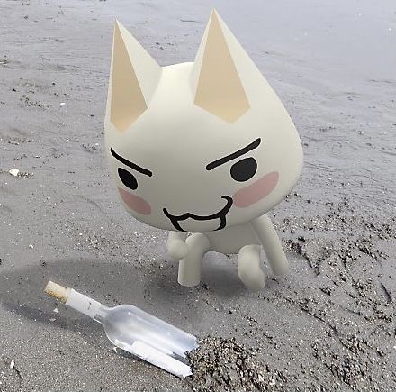 a plastic cat sitting on top of a sandy beach