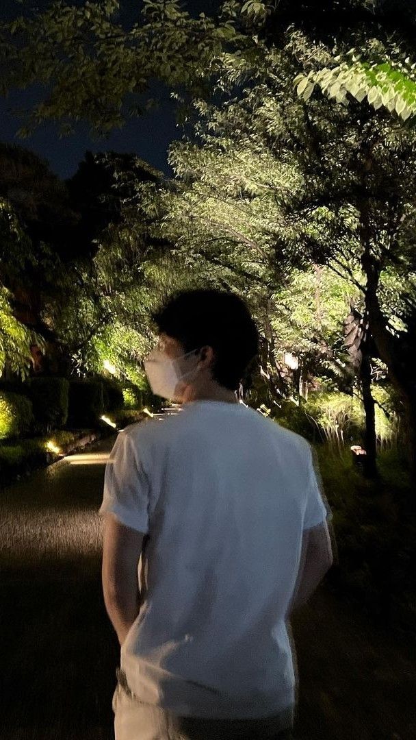 a man wearing a face mask walking down a path at night