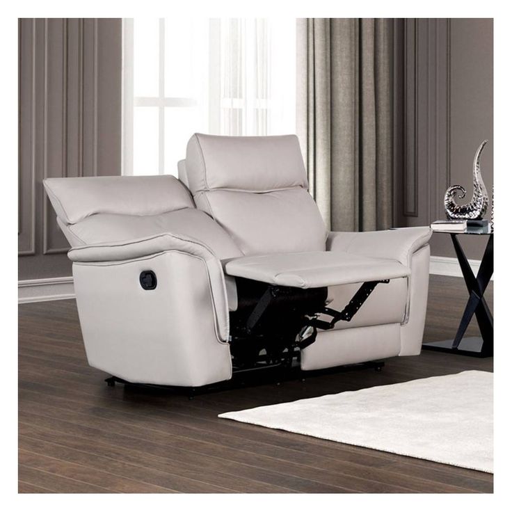 a white reclining chair sitting on top of a wooden floor next to a table