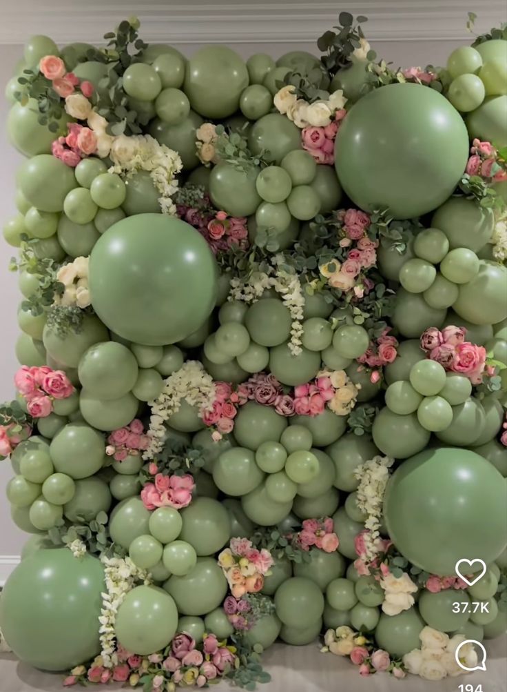 an arrangement of grapes and flowers is displayed on the wall in front of a window