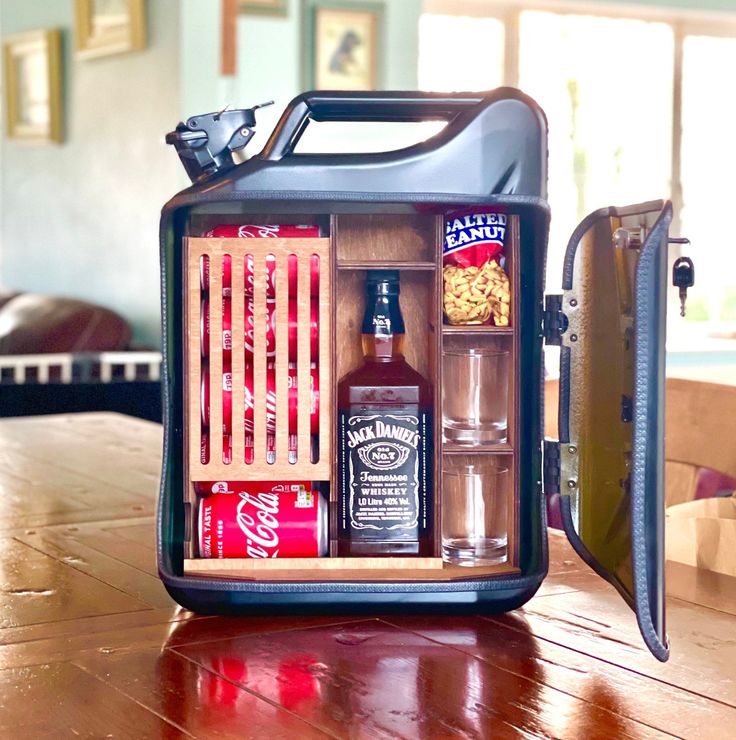 an open cooler sitting on top of a wooden table filled with bottles and liquors