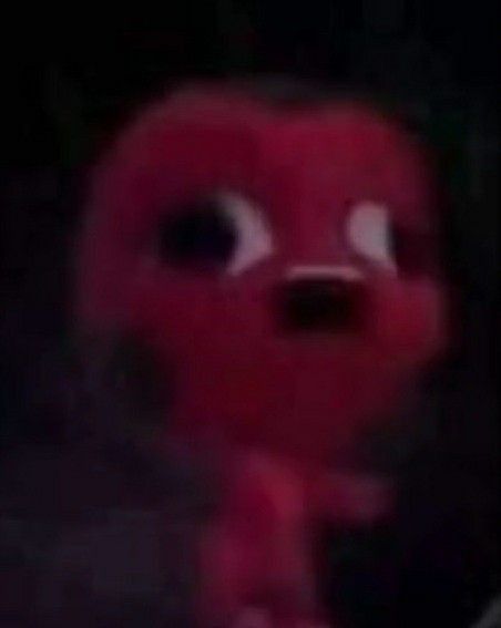 a red stuffed animal standing in the dark with its mouth open and eyes wide open