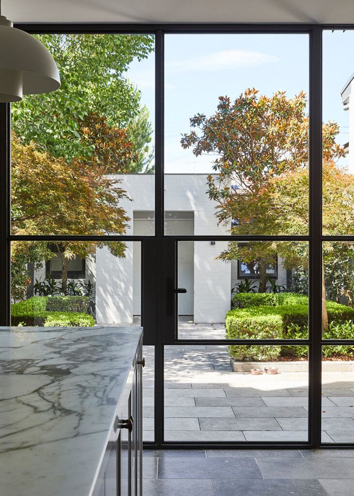 an open kitchen with marble counter tops and large glass doors that lead out to a courtyard