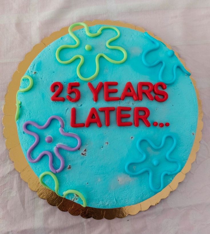 a blue cake with the words 25 years later on it sitting on a white tablecloth