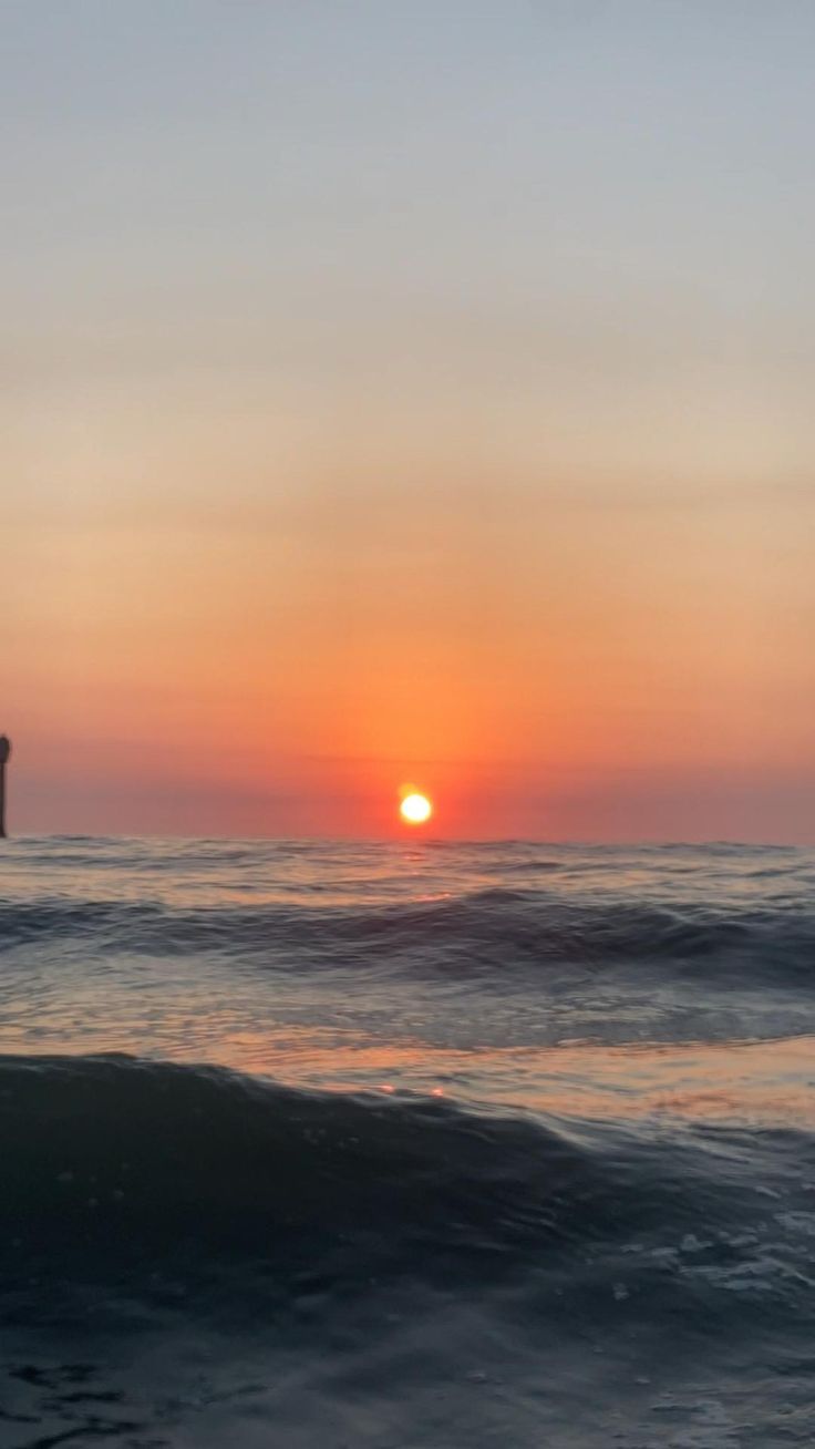 the sun is setting over the ocean with waves