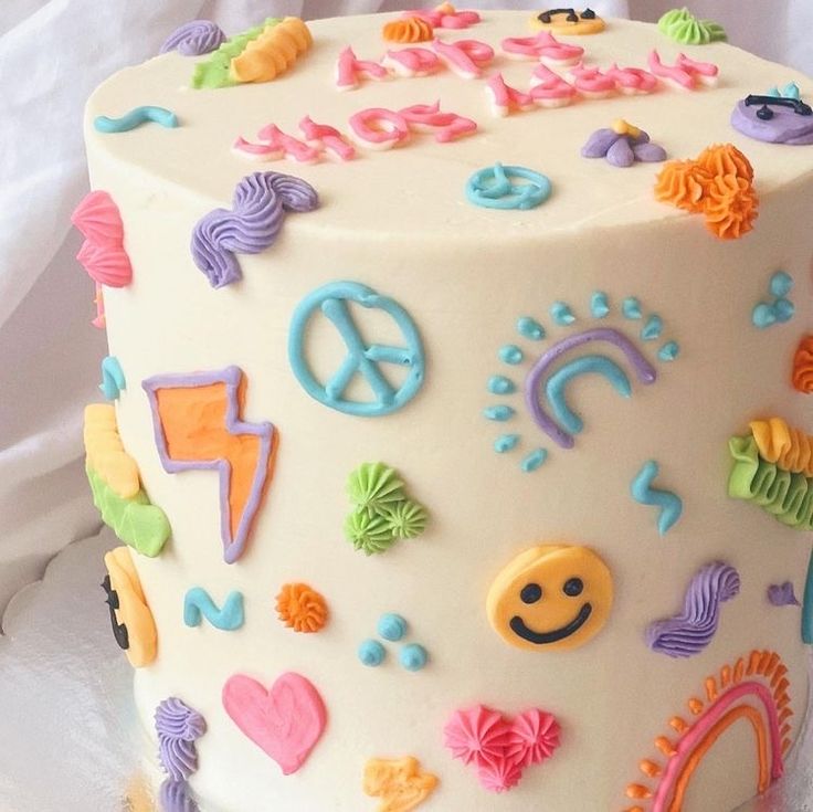 a white cake decorated with colorful fondant designs and peace signs on the frosting