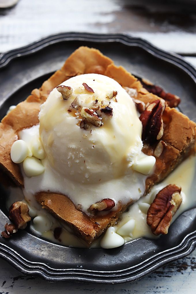 two plates with waffles, ice cream and nuts on them next to a fork