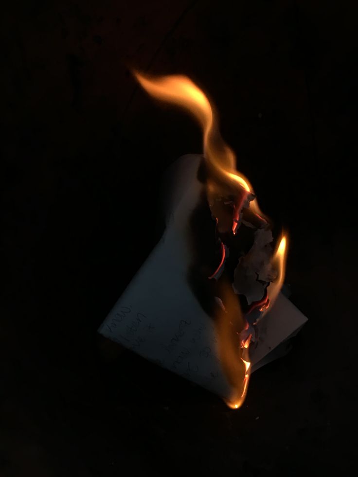 a burning piece of paper on top of a black surface with flames coming out of it