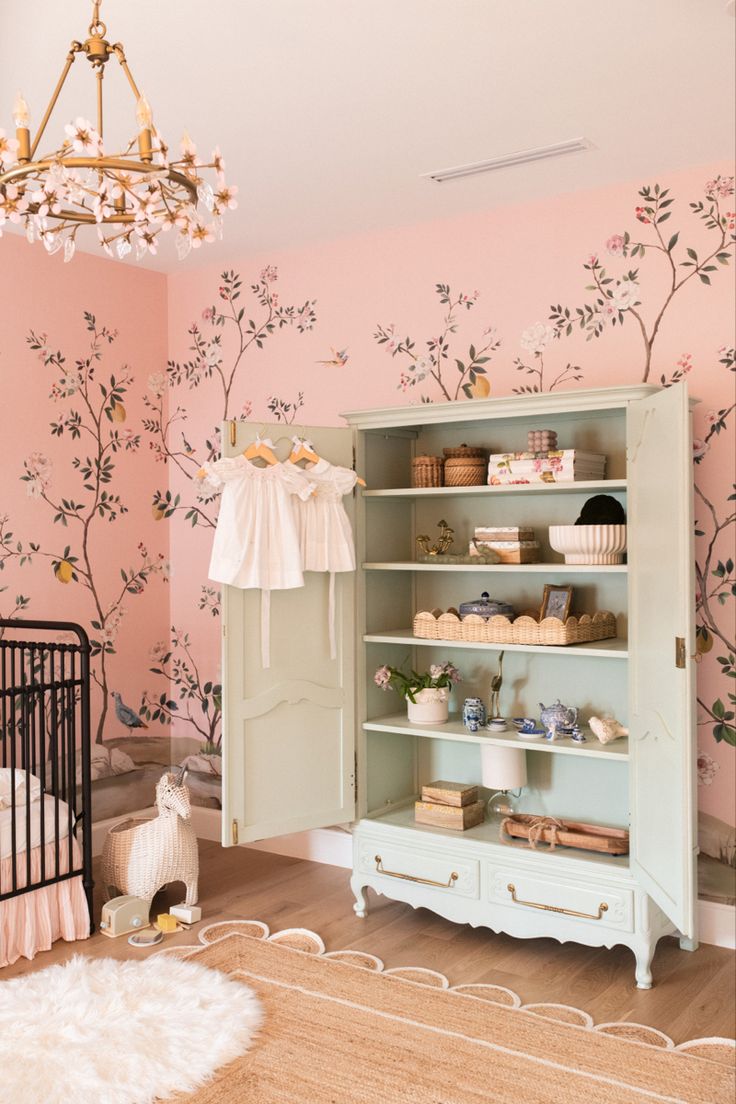 a baby's room decorated in pastel colors with pink and green wallpaper