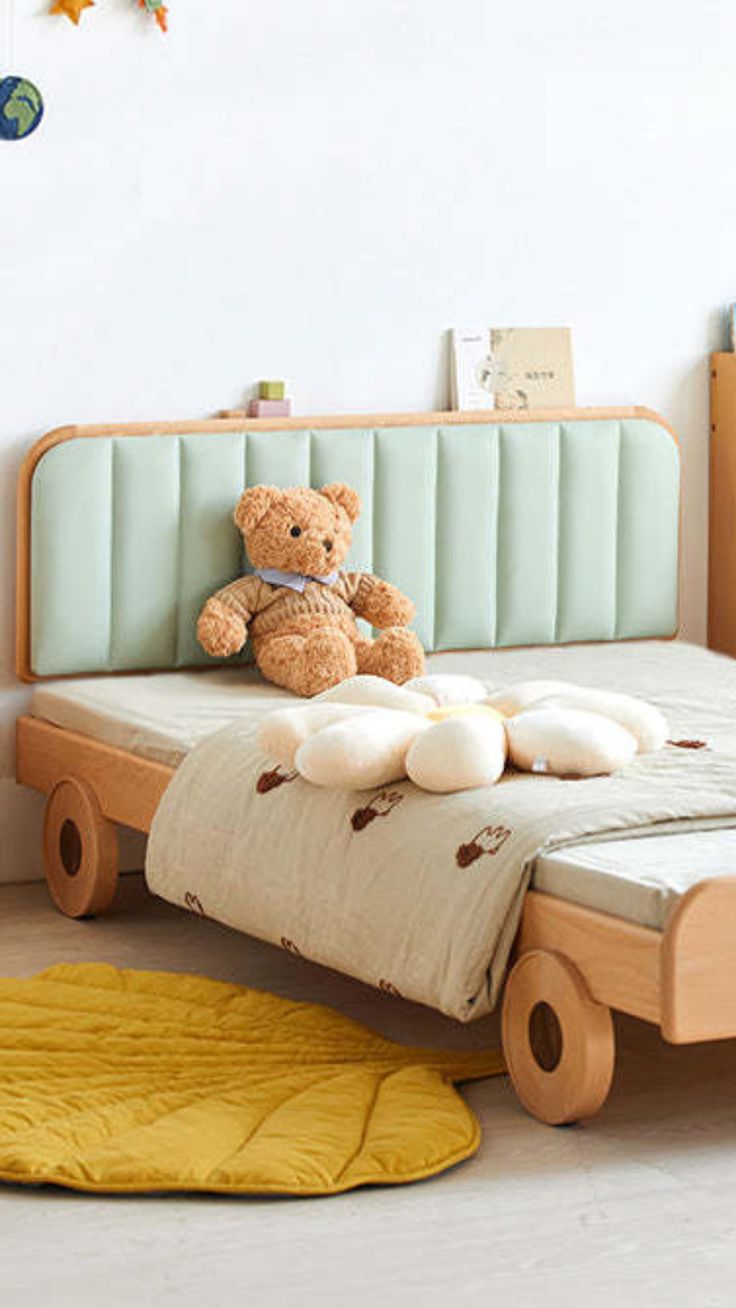 a teddy bear sitting on top of a bed in a child's room with yellow rugs