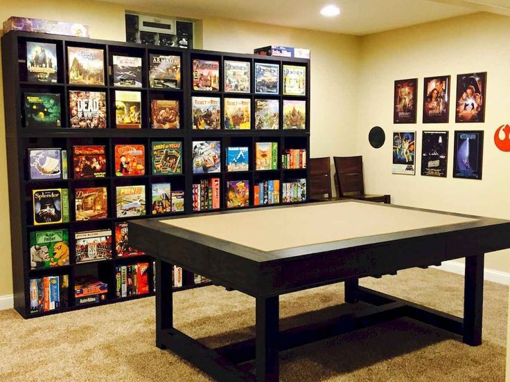 a game room with a table and several games on the wall in front of it