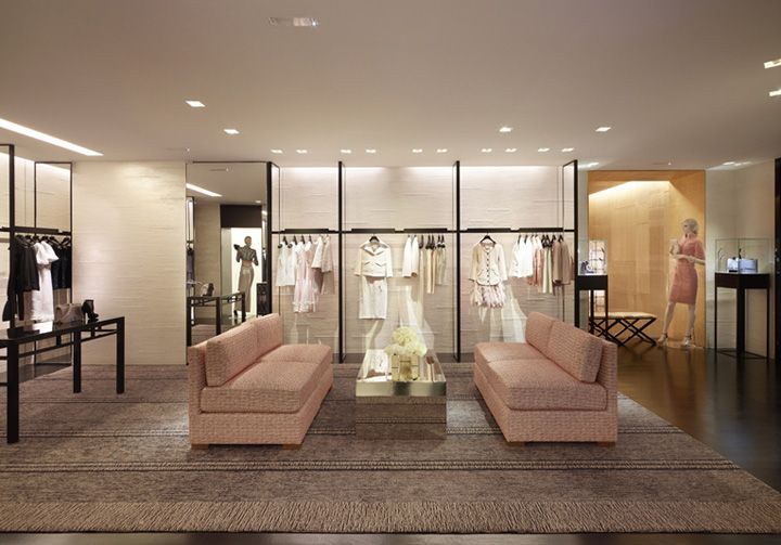 a living room filled with furniture and lots of glass walls covered in clothing racks on top of hard wood flooring