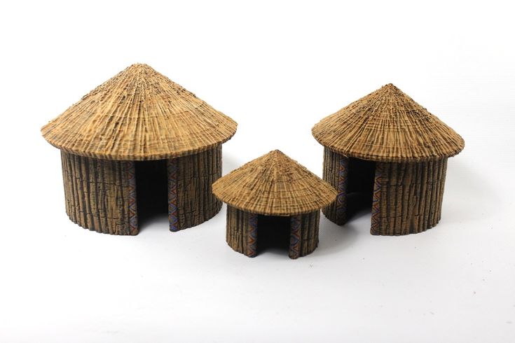 three small huts made out of straw sit next to each other on a white surface