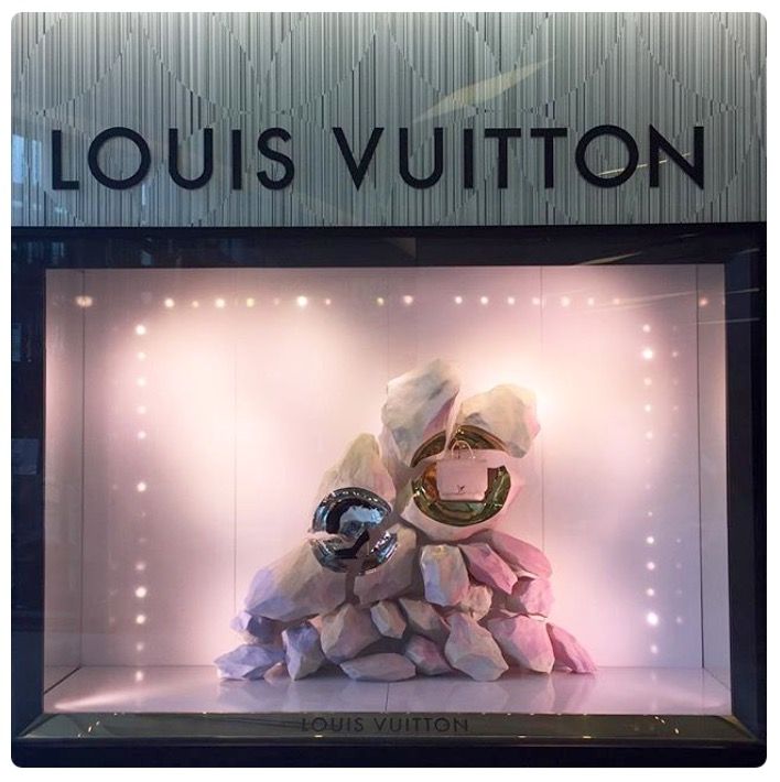 a display case with rocks in it and lights on the wall behind it that reads louis vuitton