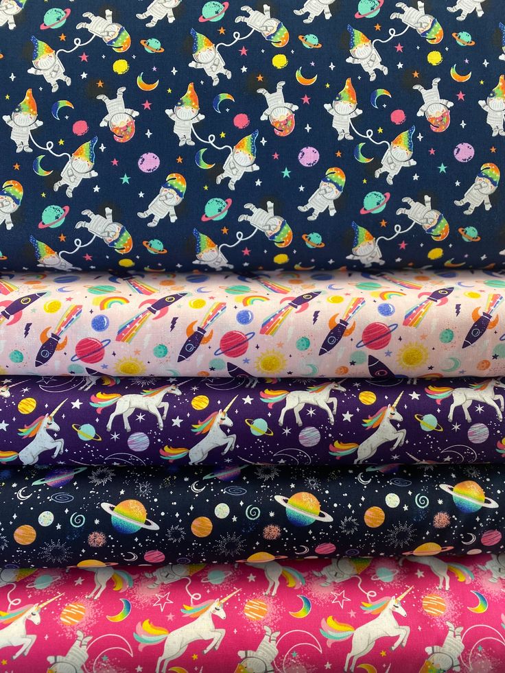 a stack of colorful fabric with unicorns and stars on the top, all in different colors